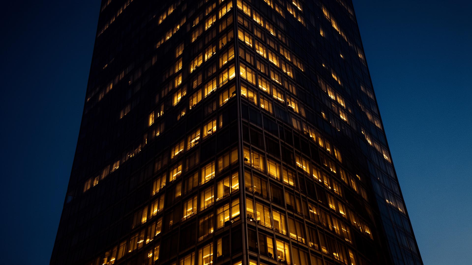 Low-angle architectural photograph of a modernist commercial tower at blue hour.